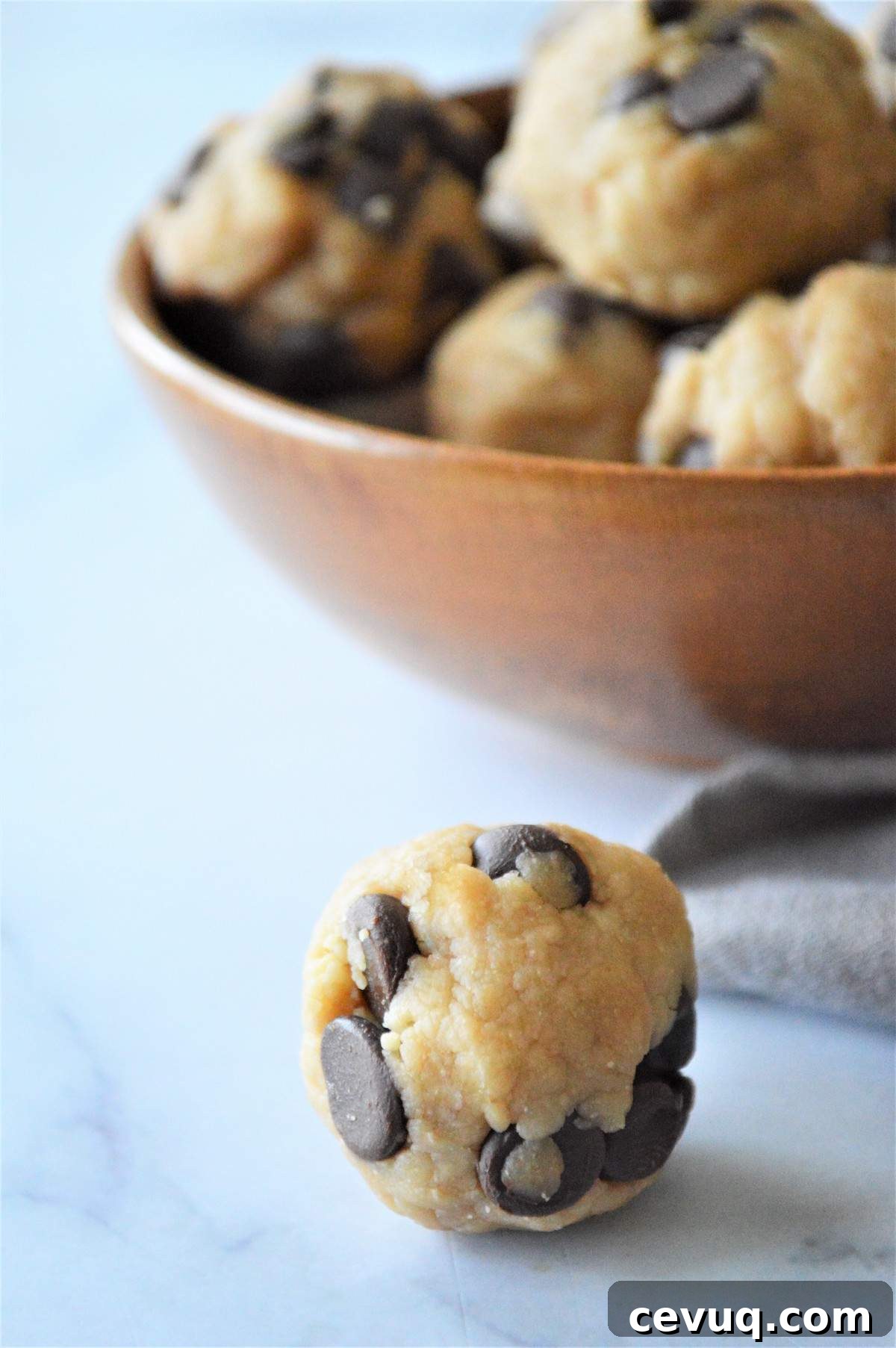 No-Bake Energy Bites Recipe for Quick, Protein-Packed Snacks 11 A cookie dough energy bite in front of a bowl of energy bite.