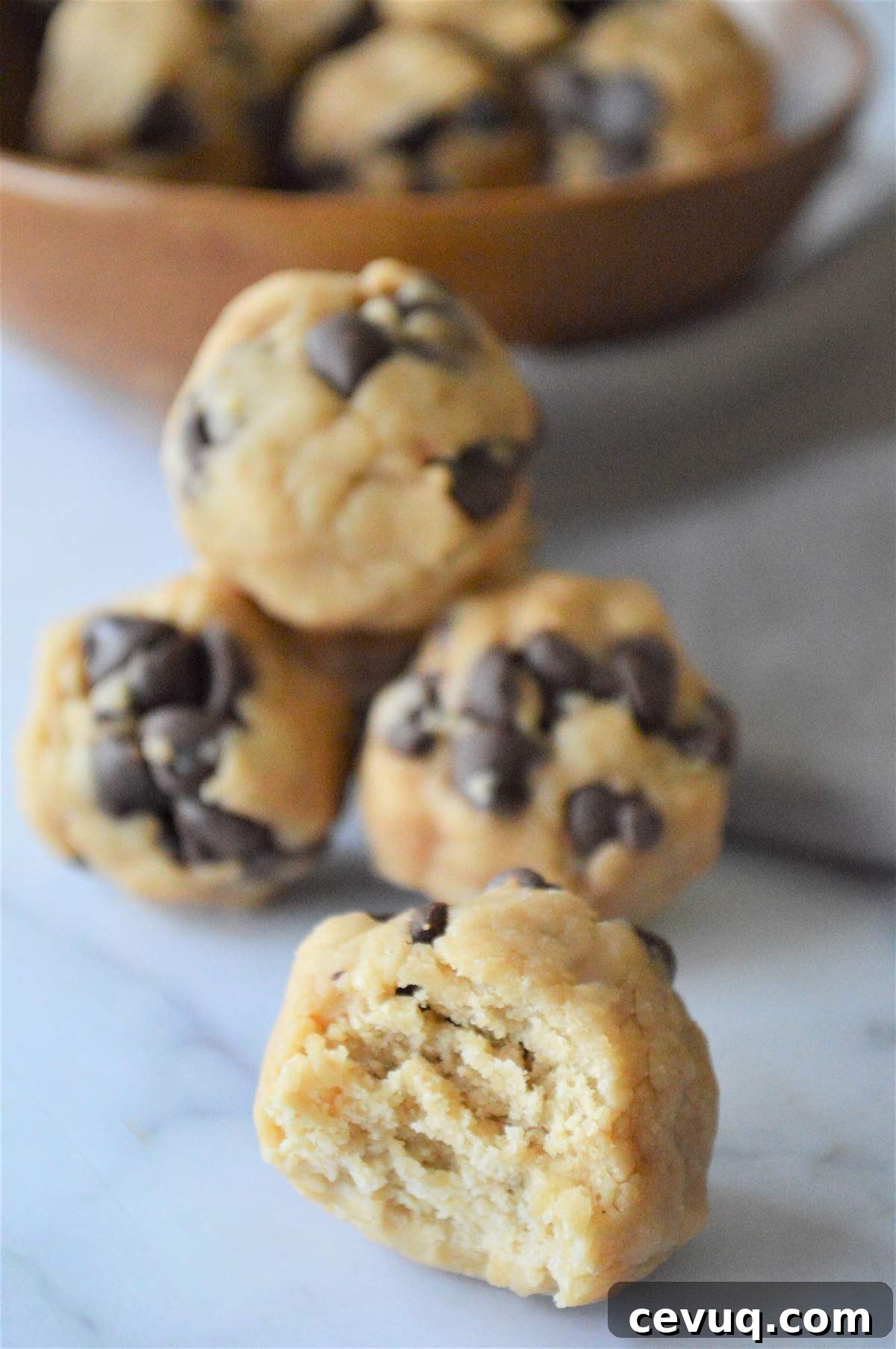No-Bake Energy Bites Recipe for Quick, Protein-Packed Snacks 4 A pile of no bake energy bites with a bowl of extras behind it.