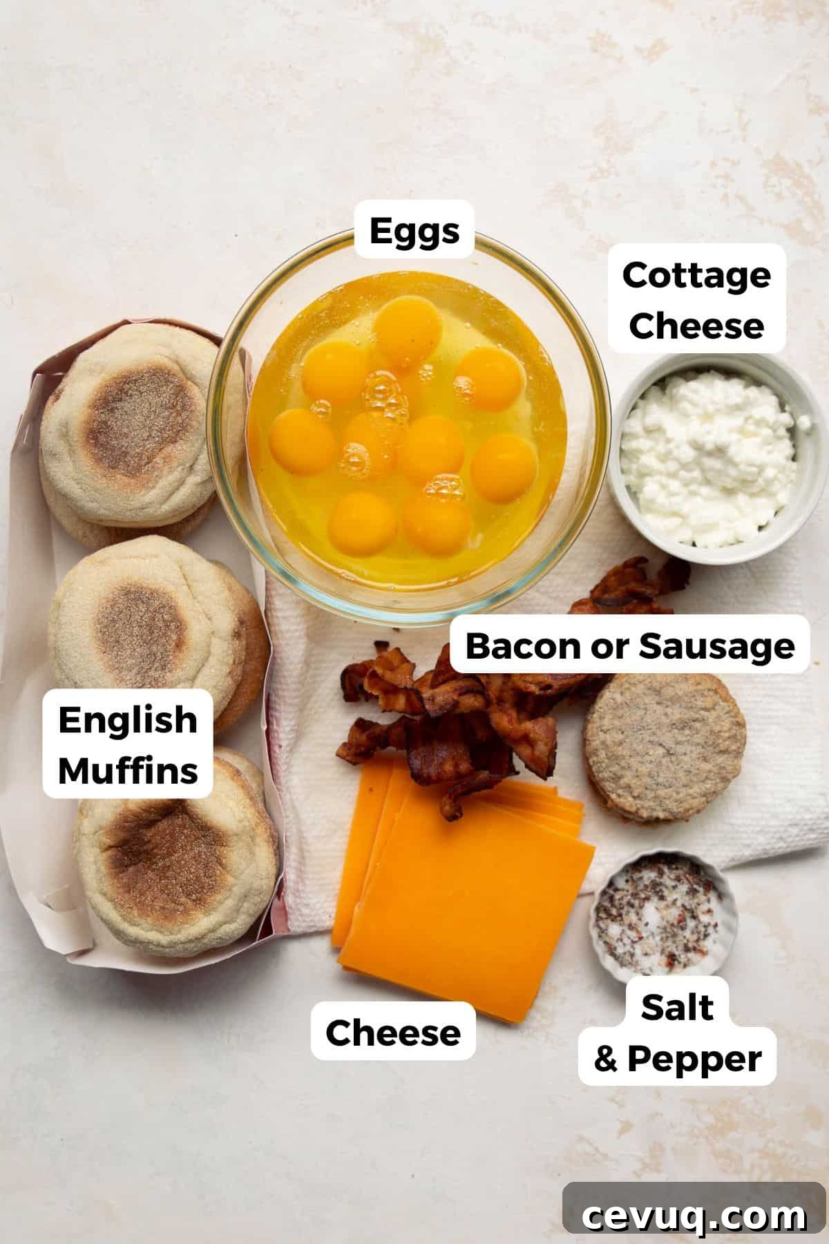 Ingredients for high-protein freezer breakfast sandwiches including eggs, cottage cheese, English muffins, sausage or bacon, cheese, salt, and pepper.