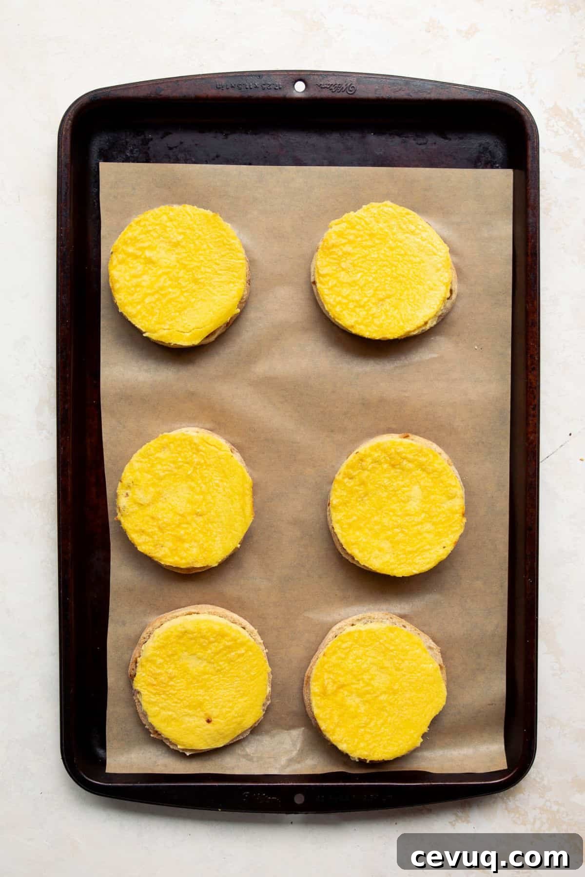 Egg rounds placed on English muffin halves for meal prep breakfast sandwiches.