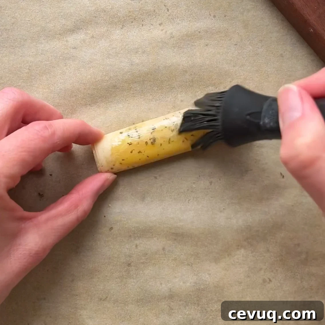 A person uses a silicone brush to apply olive oil onto a phyllo feta fry.