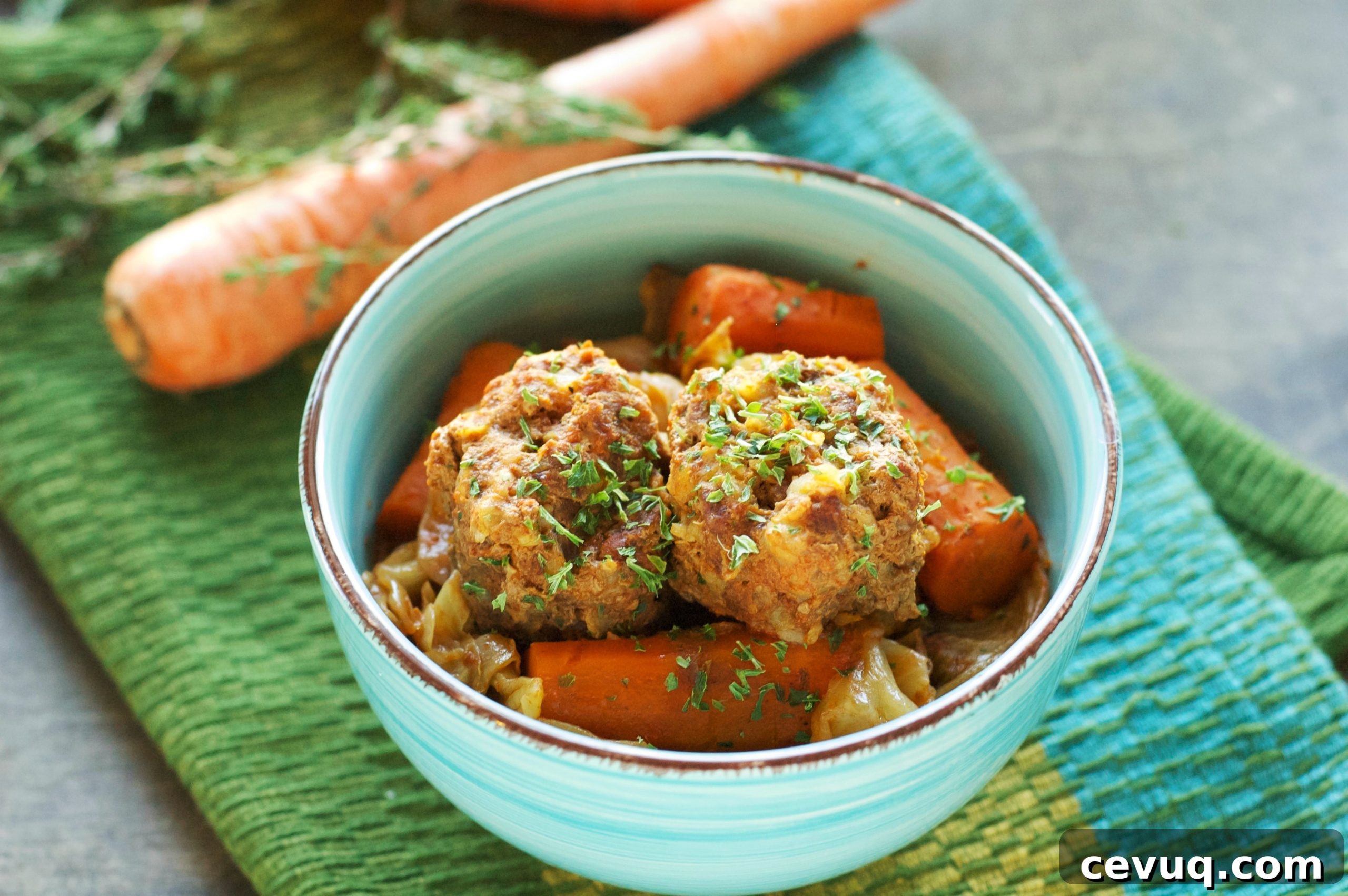 green bowl with meatballs and carrots with one carrot in background