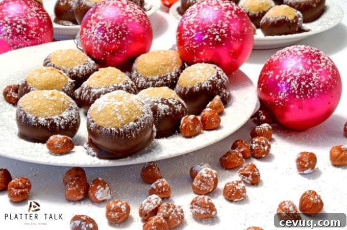 Plate of holiday treats with ornaments and hazelnuts, dusted with powedered sugar.