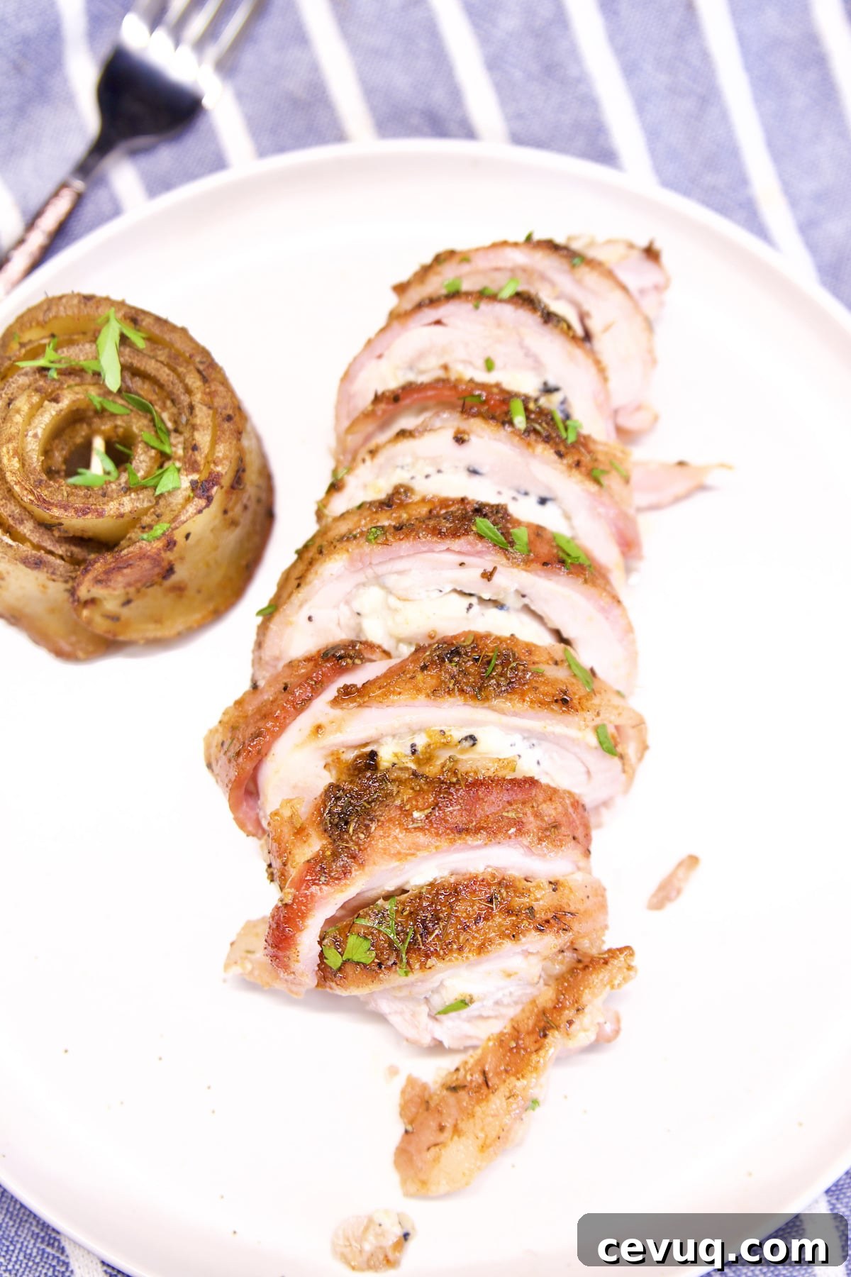 plate with sliced bacon wrapped stuffed chicken.