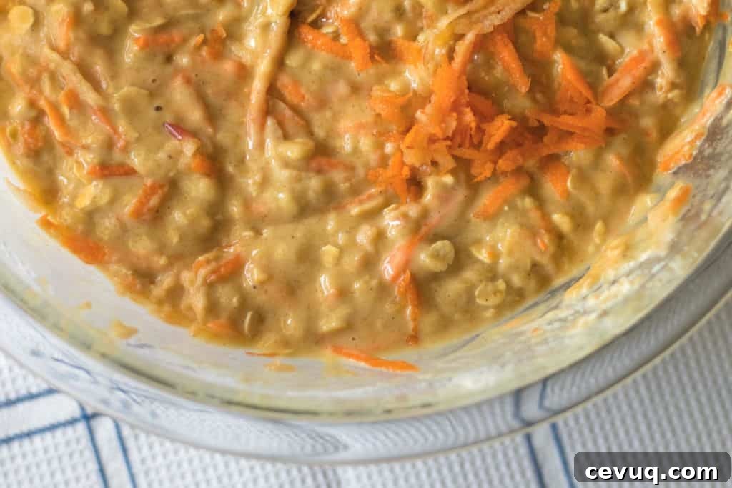 apple cinnamon oatmeal muffin batter with shredded carrots in a glass bowl