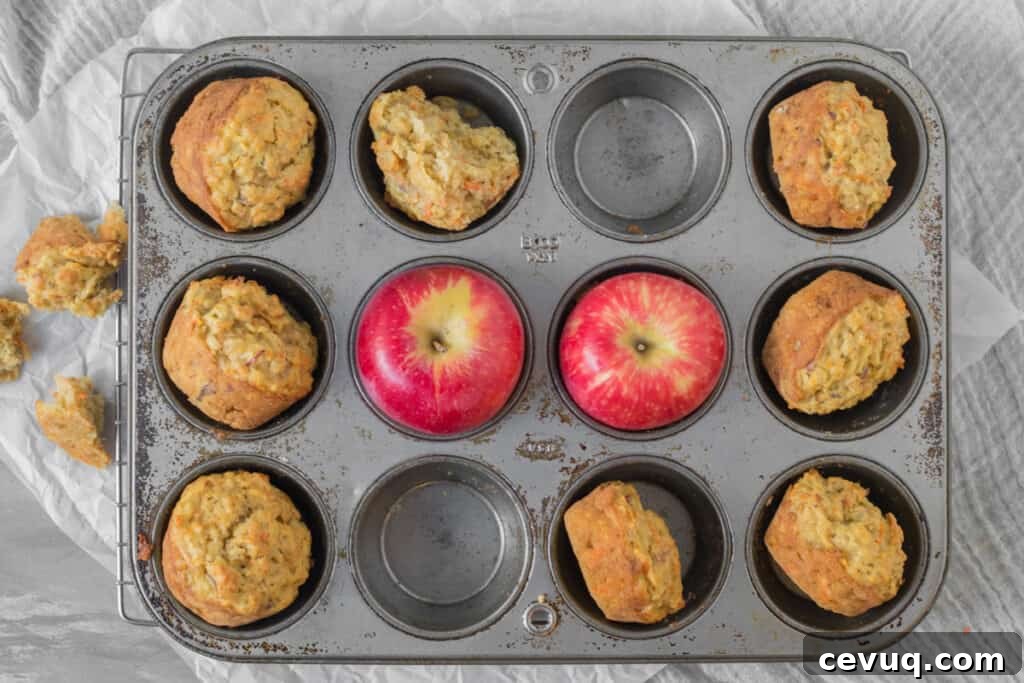 apple carrot muffins in a muffin tin with apples
