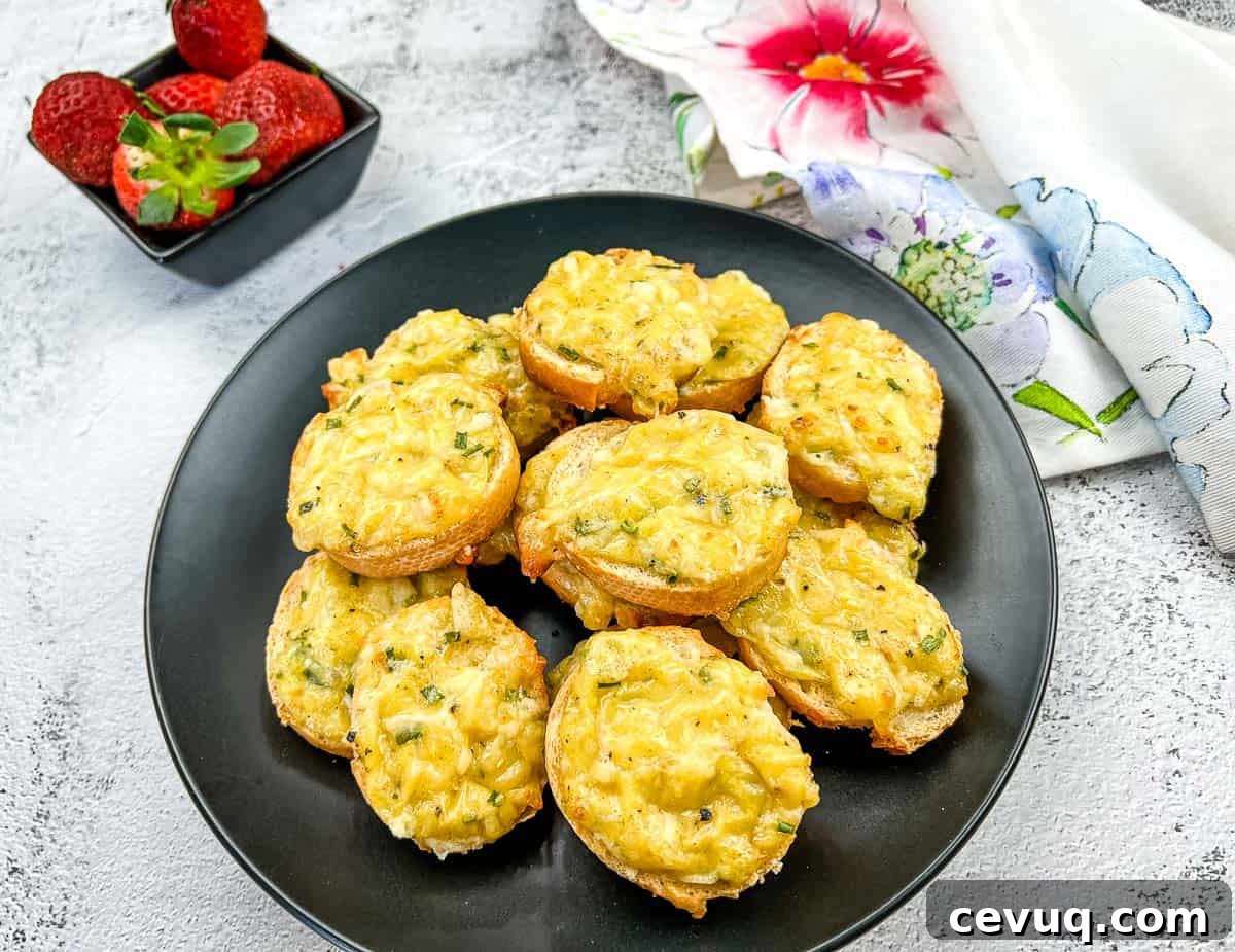 Bite-sized Cheese Toasties on a black plate with a small bowl of strawberries and a floral napkin nearby.