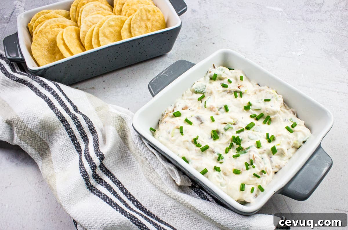 A bowl of cold crab dip with crackers and chives.