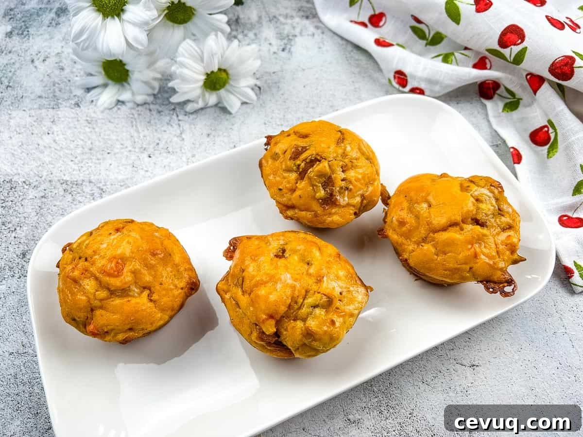 Four pizza muffins on a white plate with flowers.