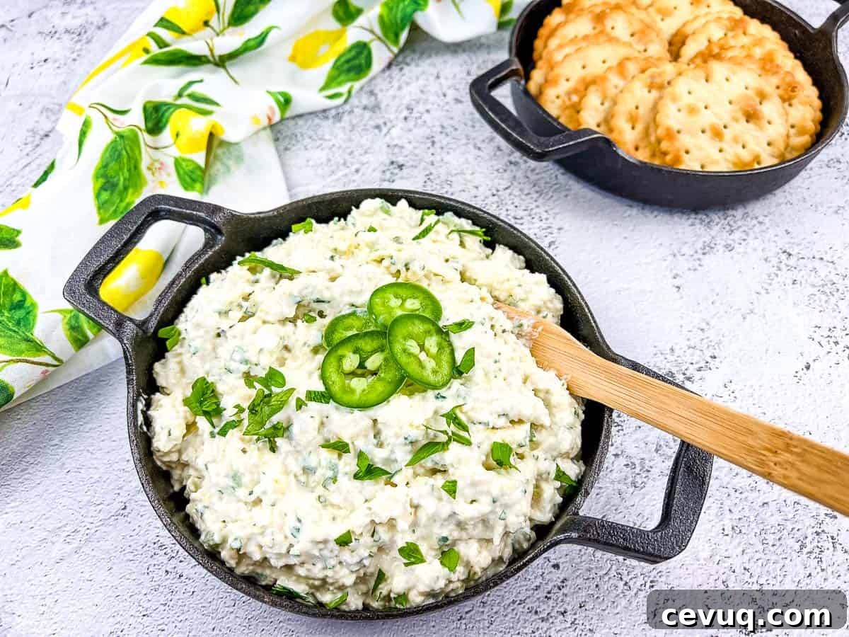 Artichoke Jalapeno Dip in a black bowl with crackers nearby.