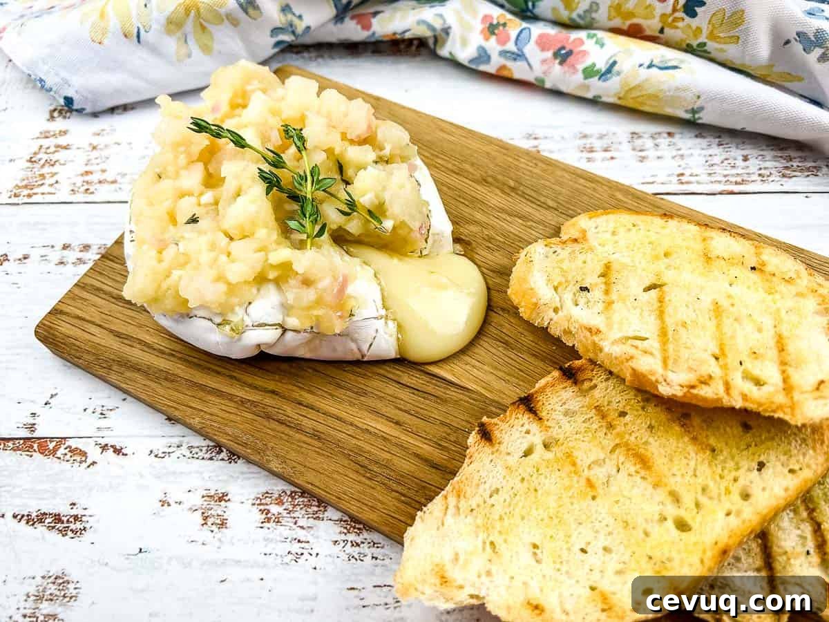 A chunk of oozing brie with apple chutney on a board.