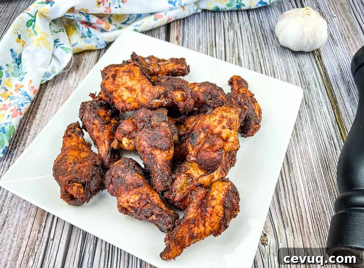Smoked dry rubbed chicken wings on a white plate with garlic.