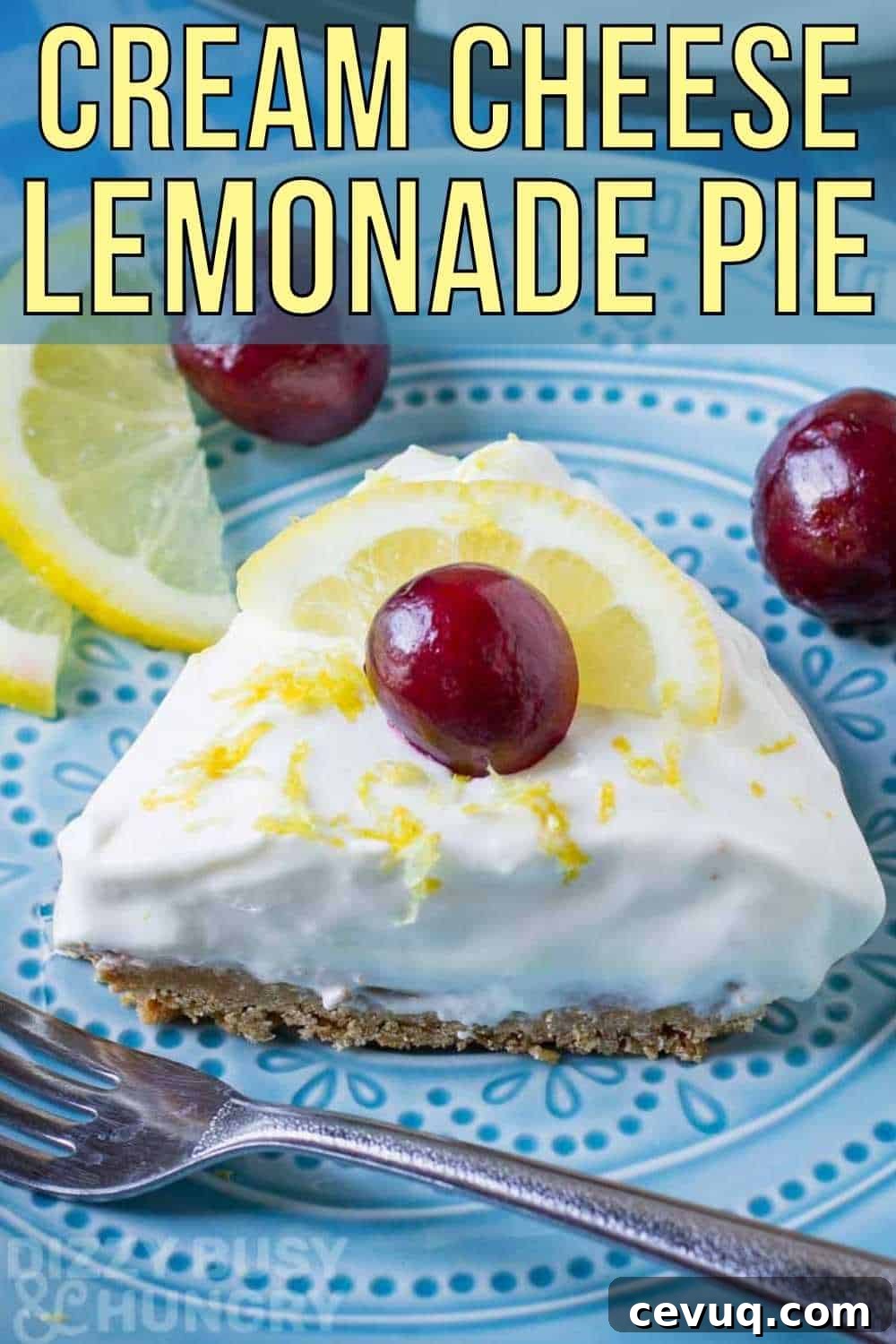 Close up shot of a slice of lemon pie garnished with a whole cherry on a blue plate with a fork, lemon slices, and more cherries on the side.