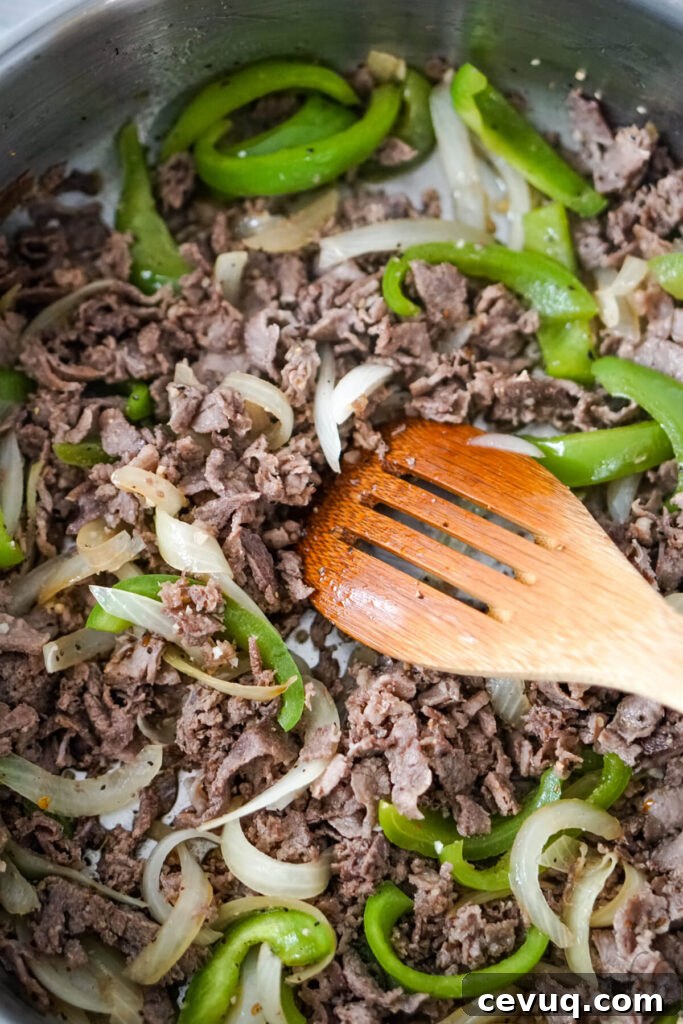 The steaks, onions, and peppers and stirred together with a wooden spoon.