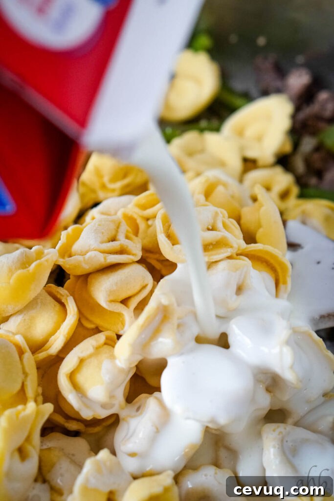 The frozen tortellini and heavy cream are added to the pan.