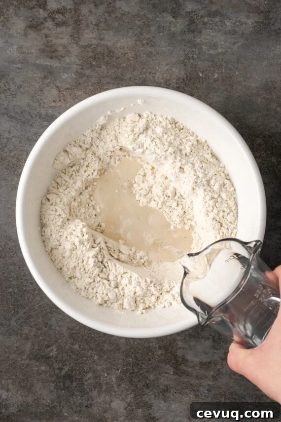 Water added to Bisquick in a white bowl.