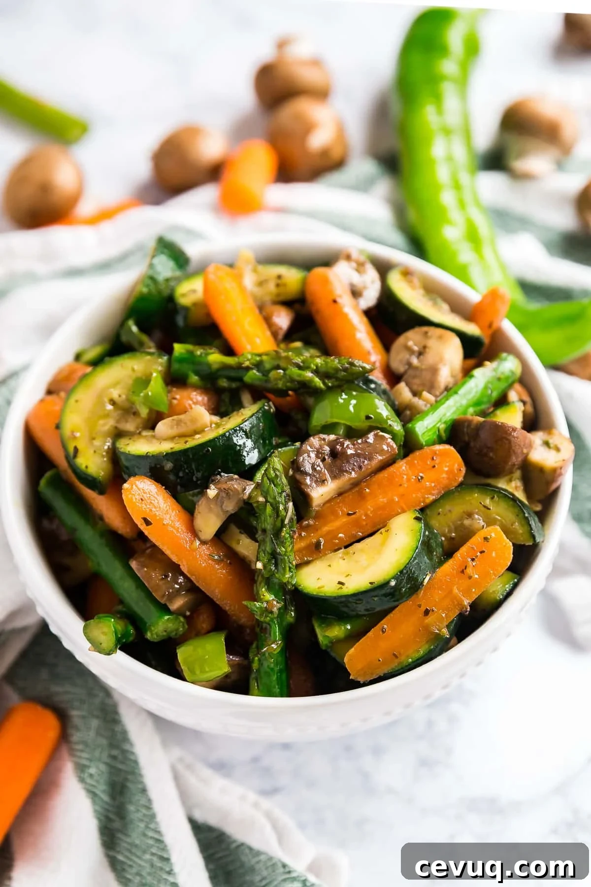 A white bowl of mixed vegetables with raw veggies behind it.