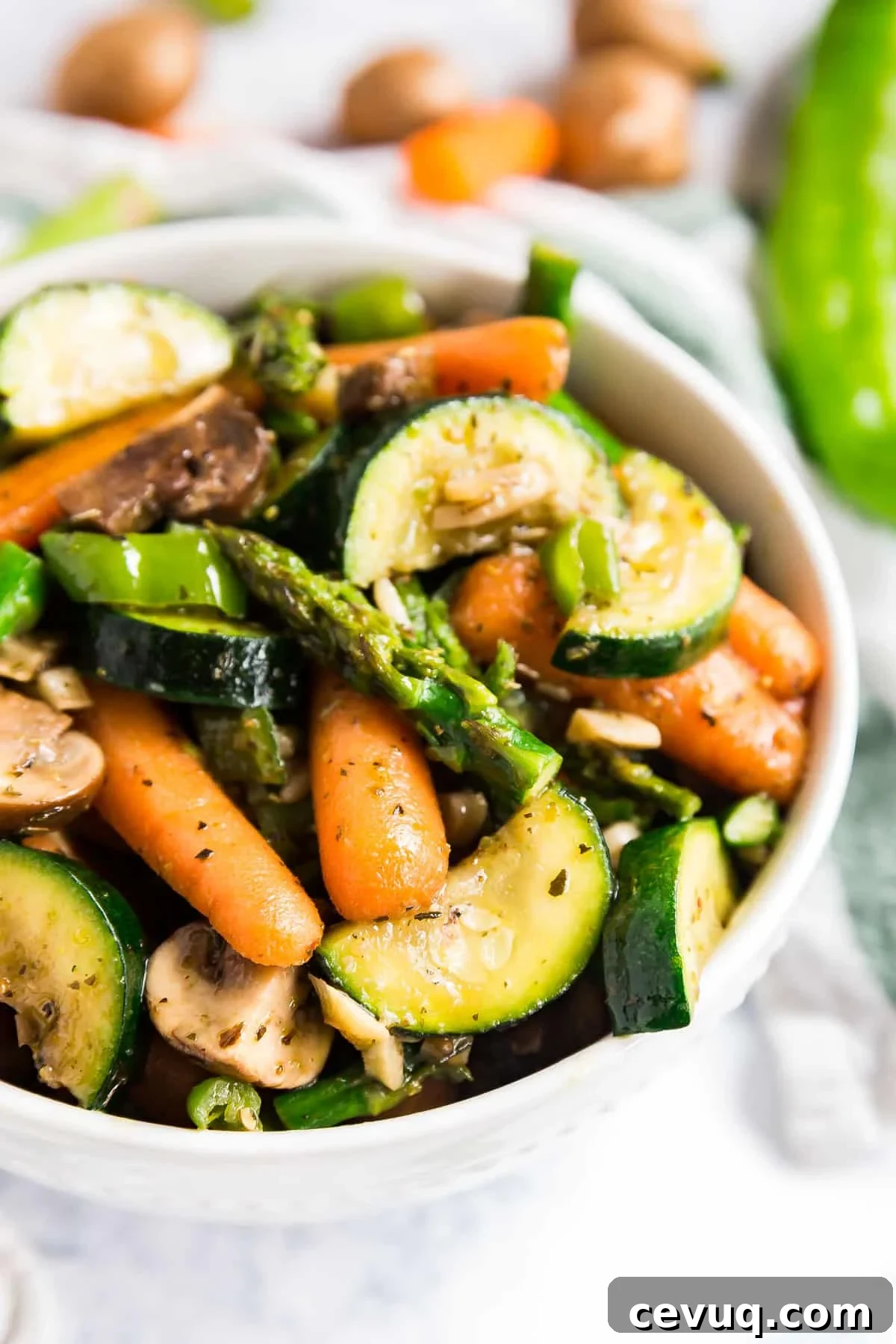 A close up image of mixed veggies in a white bowl with raw veggies in the background.
