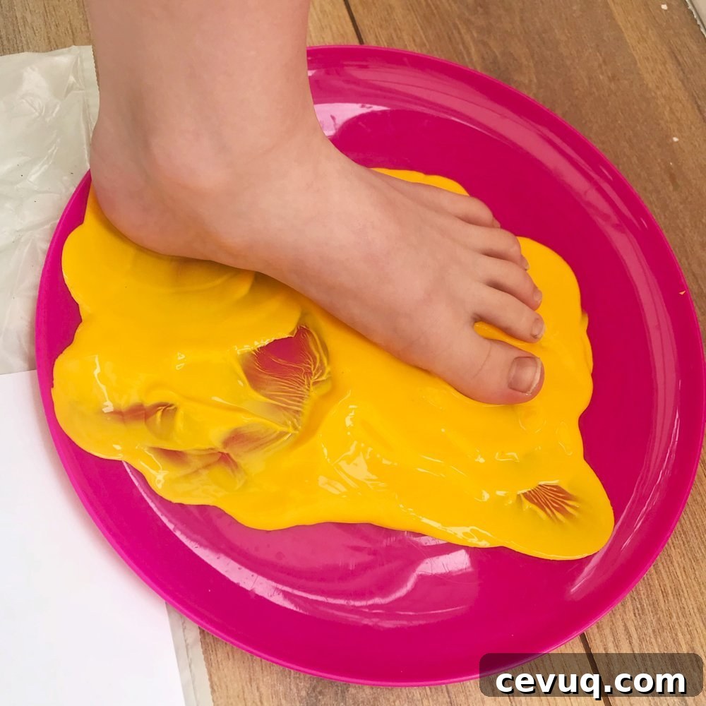 small child making painted footprints with yellow paint