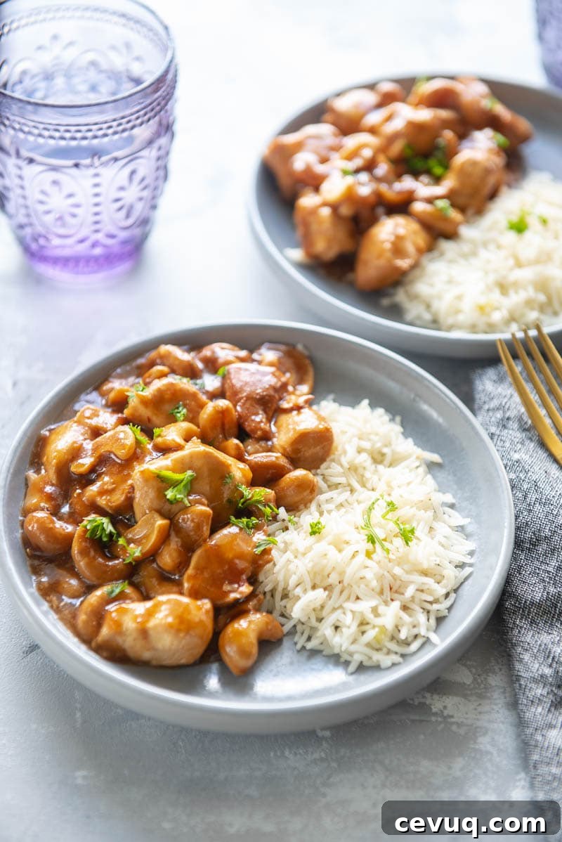 cashew chicken with rice on two plates with a glass of water