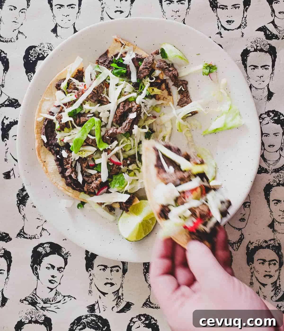 A plate with a Mexican tlayudas and wedge of lime. The background is a collage of sketches of Mexican artist Frida Kahlo