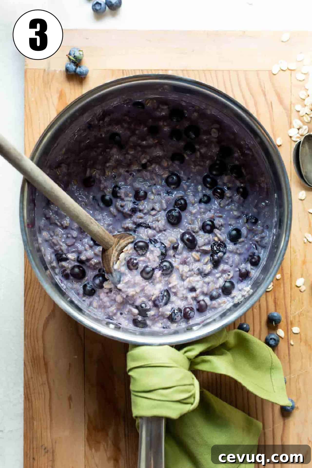 Saucepan filled with cooked, purple colored oatmeal with fresh blueberries.