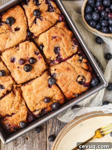 blueberry butter swim biscuits in a metal baking pan on a wooden surface.