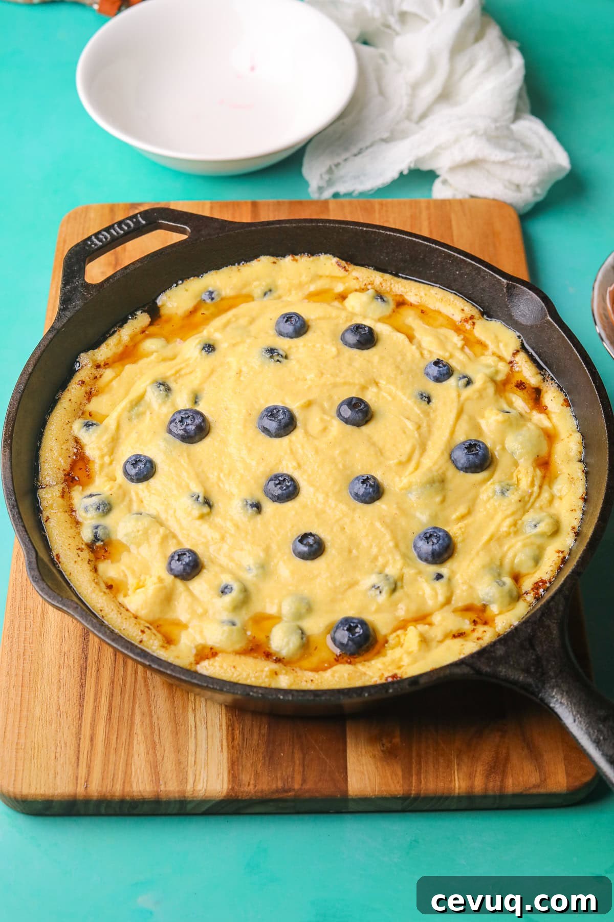 blueberry cornbread batter in a hot cast iron skillet before baking.