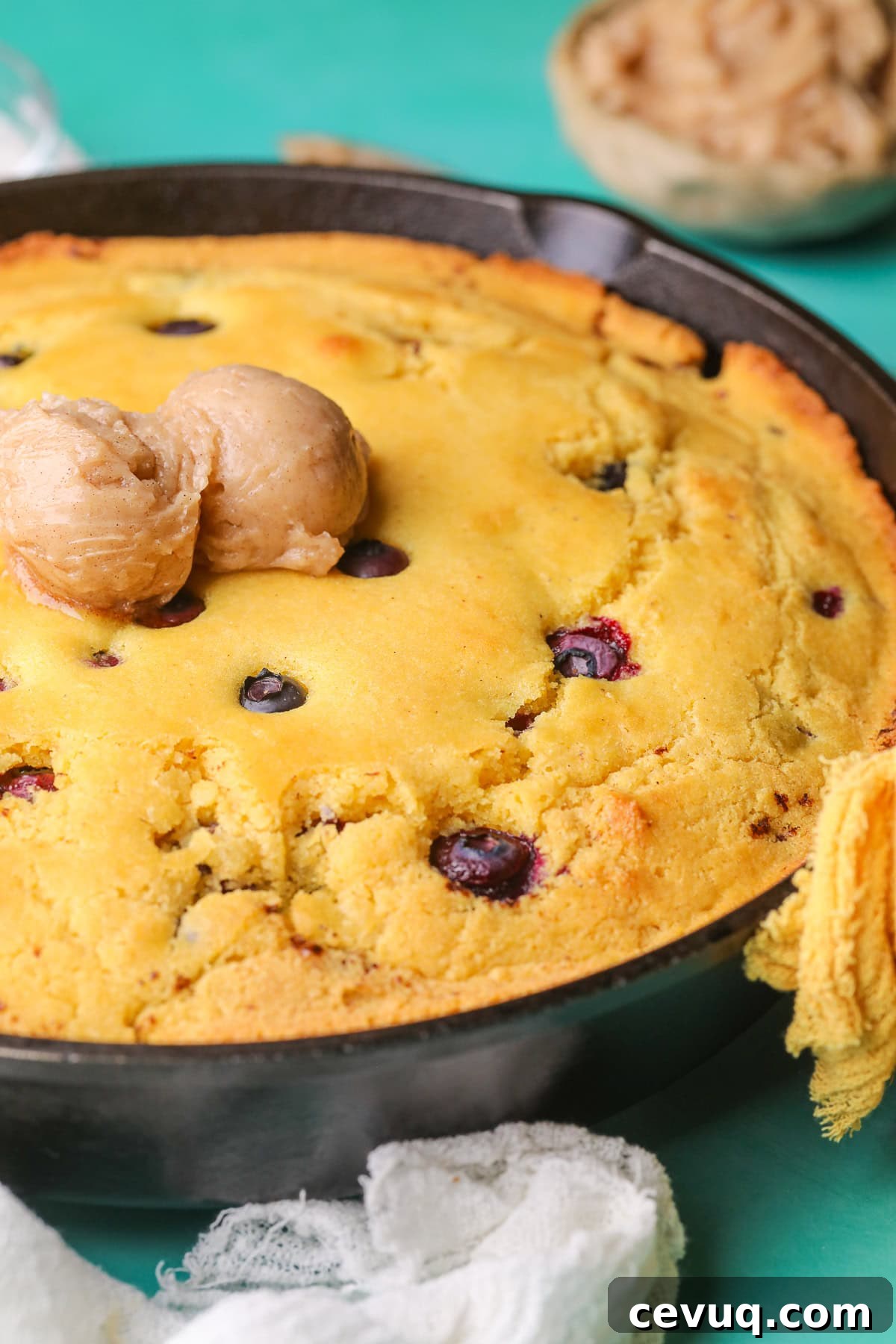 Blueberry cornbread with cinnamon honey butter in a cast iron skillet.