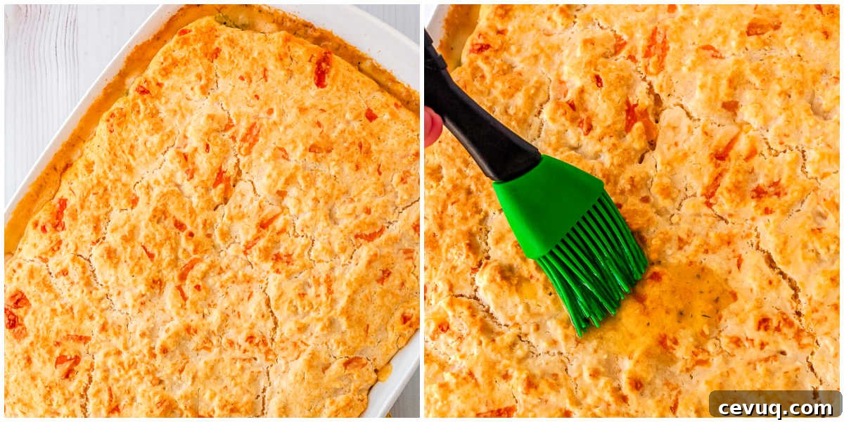 Golden baked chicken pot pie with biscuit crust being brushed with garlic herb butter.