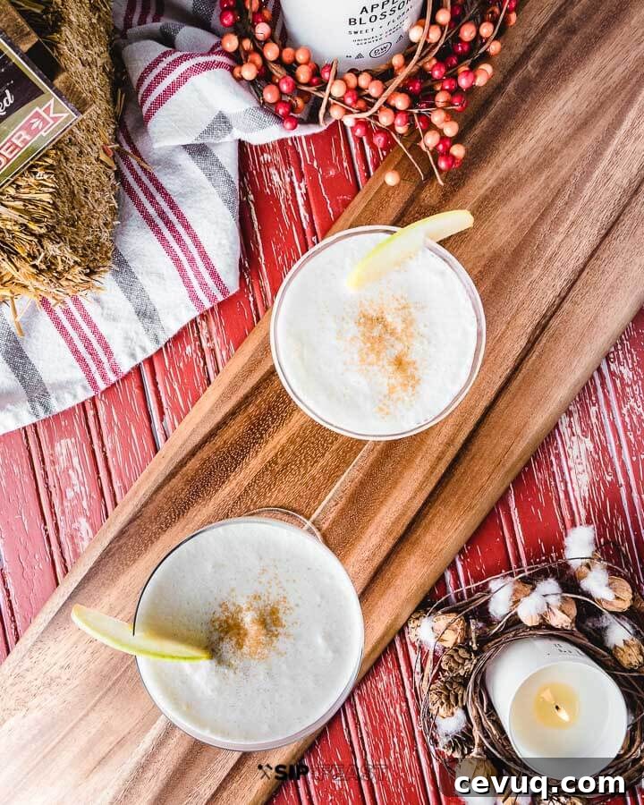 Two coupe glasses filled with apple pie martini with fall decor in background.
