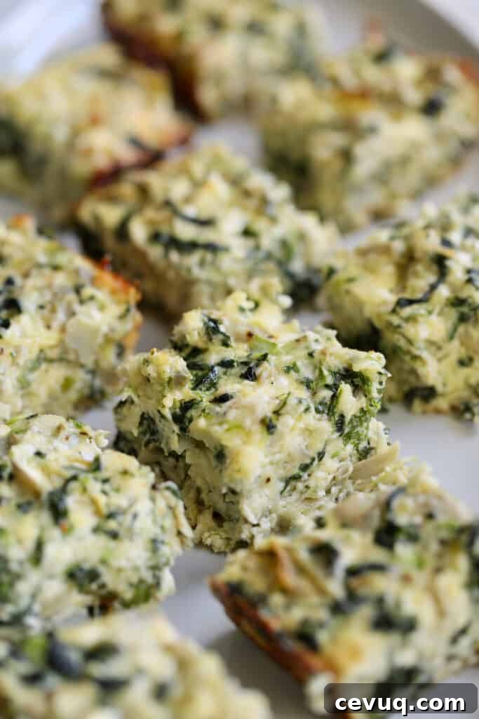 Close-up photo of Spinach Artichoke Squares on white platter.