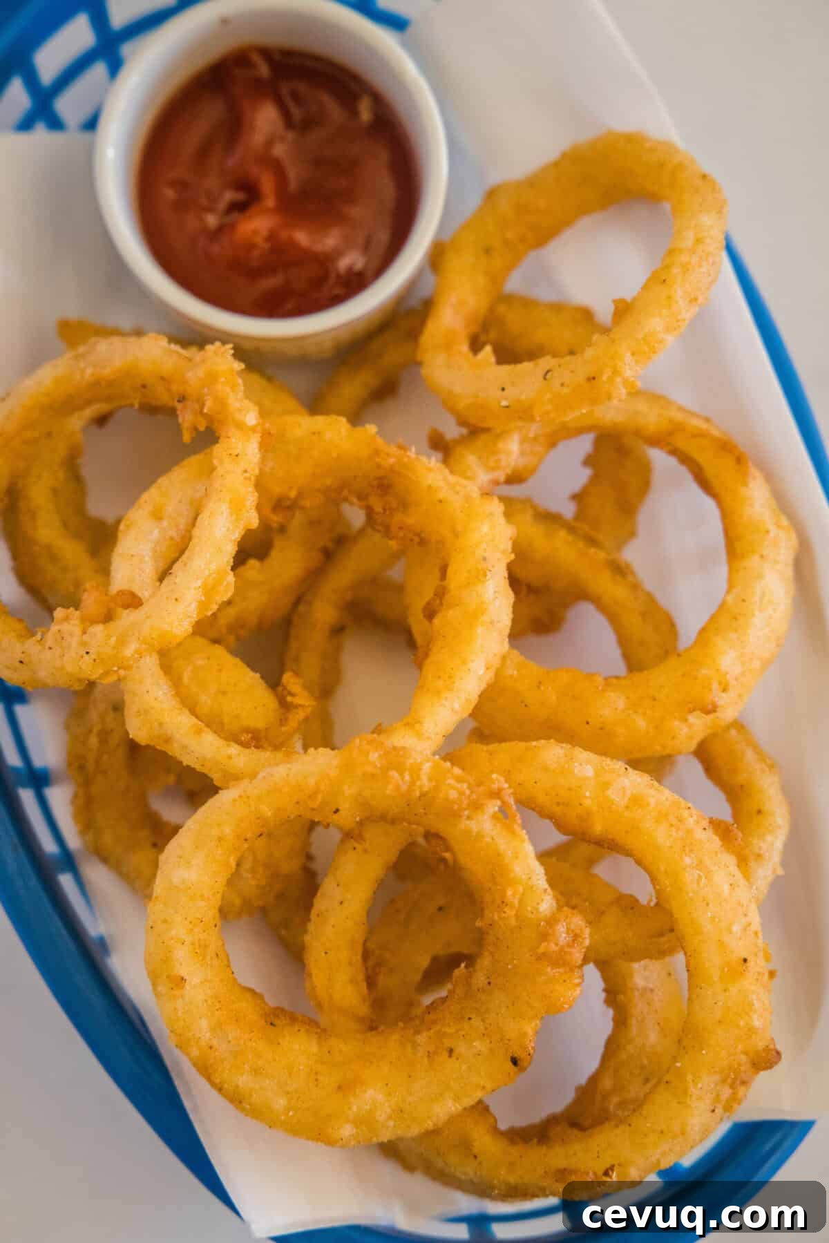 looking down on basket of onion rings and ketchup