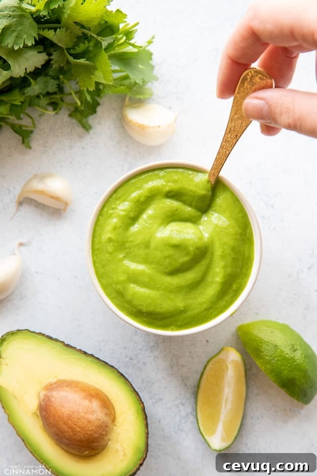 overhead shot of a small bowl with creamy cilantro avocado lime sauce with a golden spoon