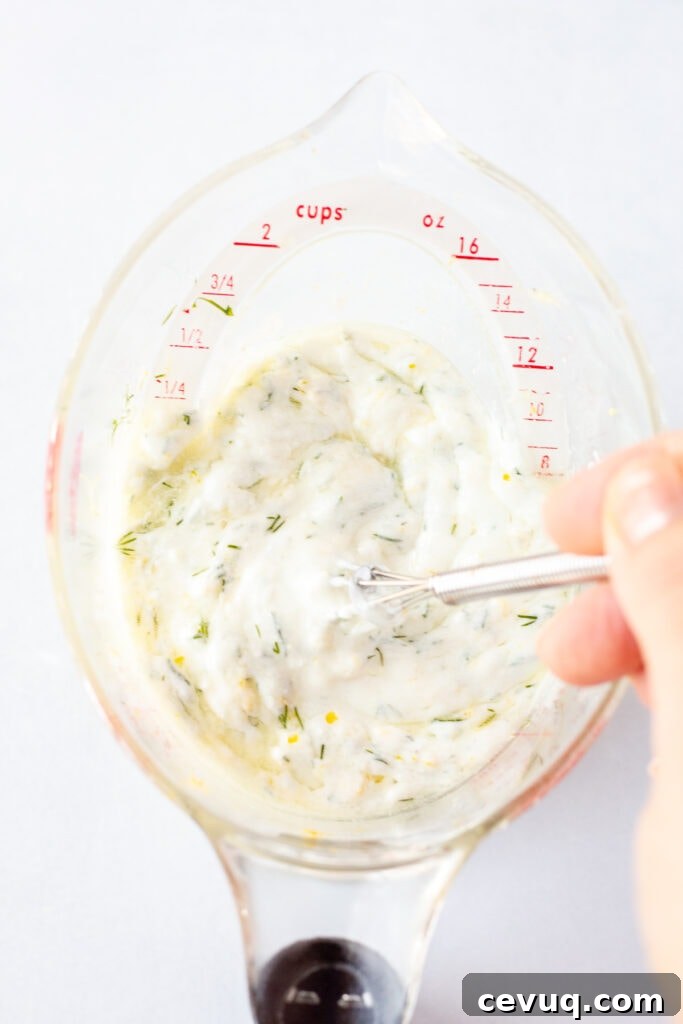 Whisking together ingredients for Greek yogurt marinade in a measuring cup.