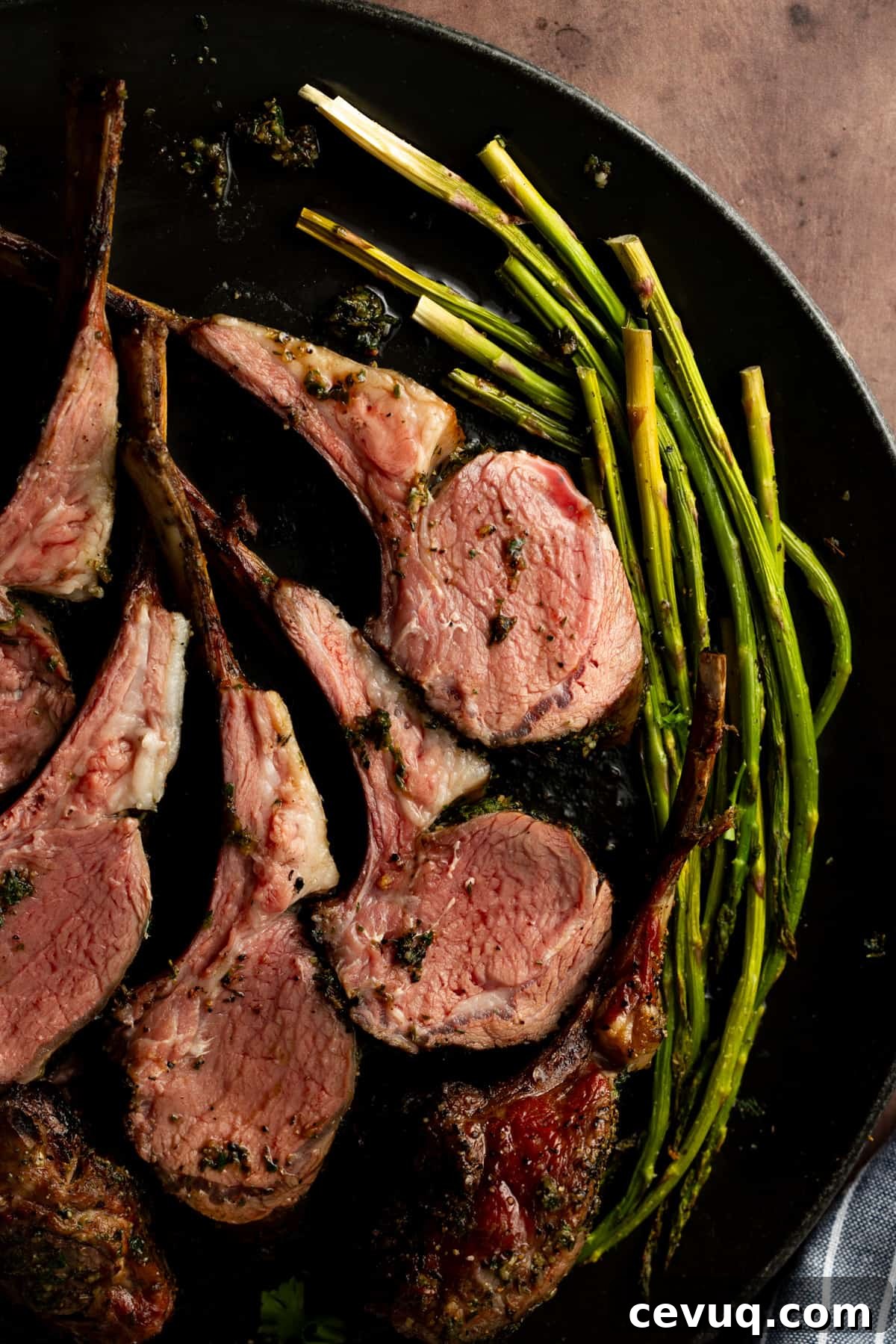 Lamb chops on black plate with a side of asparagus.