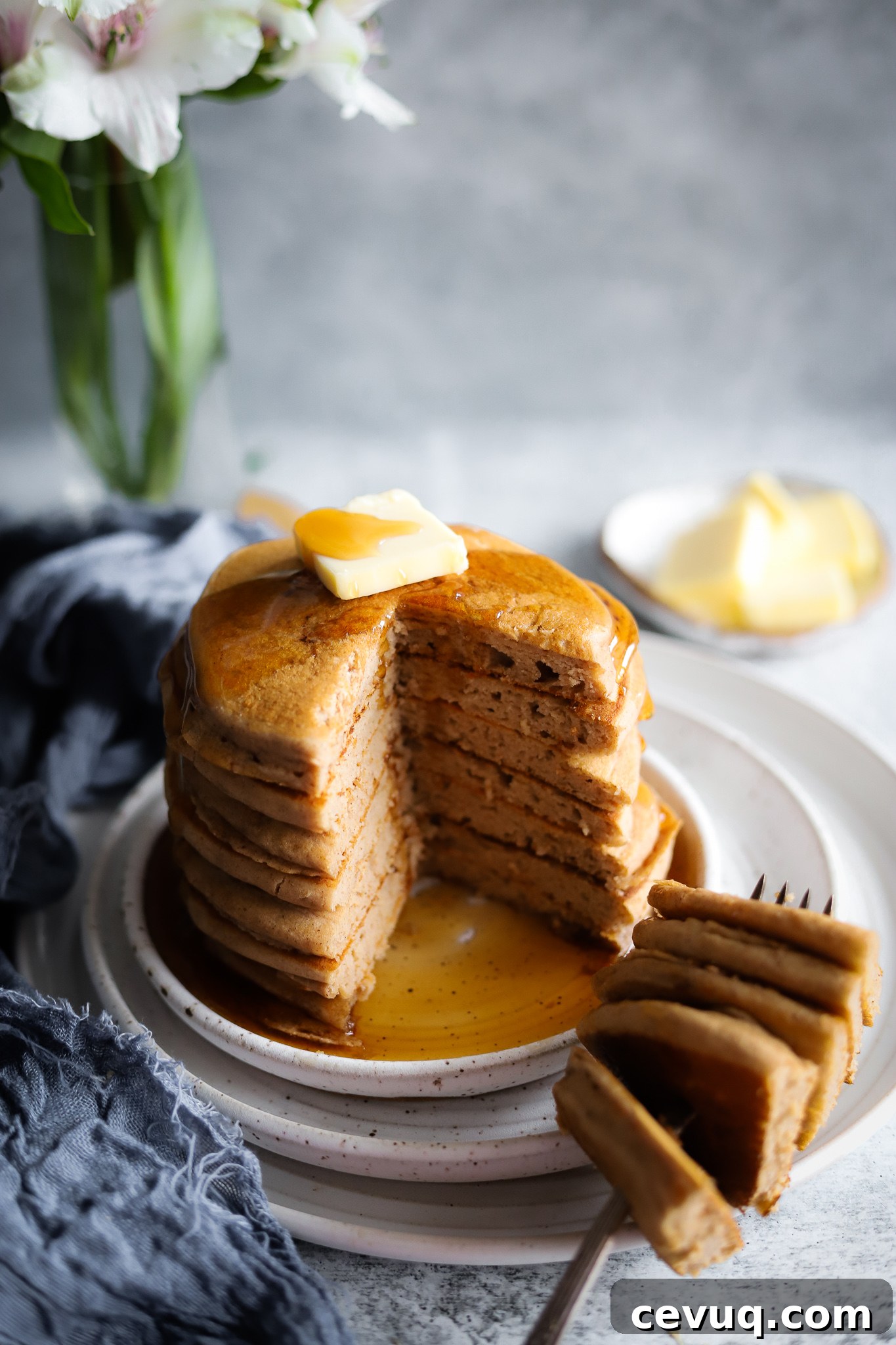 A tall stack of fluffy pancakes with strawberries on top