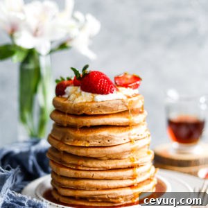 Tall stack of fluffy pancakes with strawberries on top