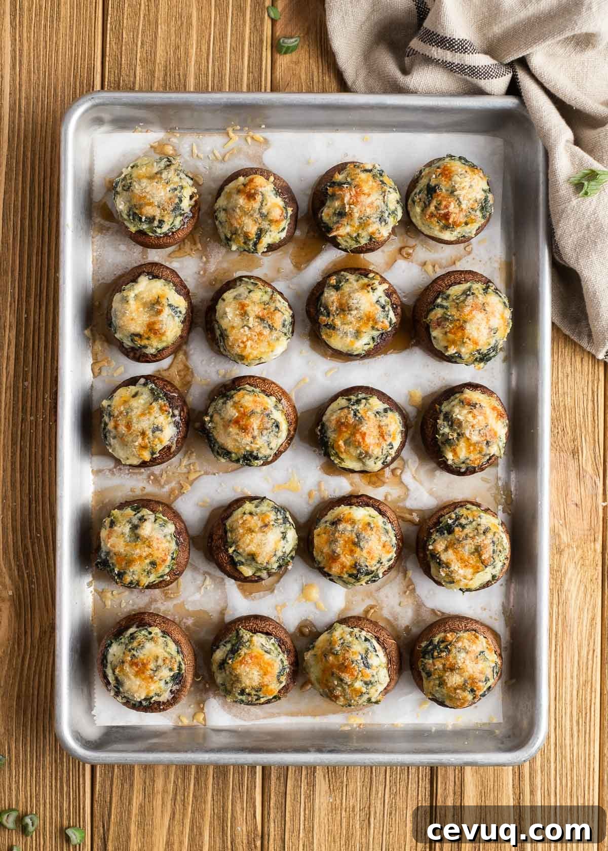 an overhead shot of all 20 spinach stuffed mushrooms baked on a parchment paper lined pan