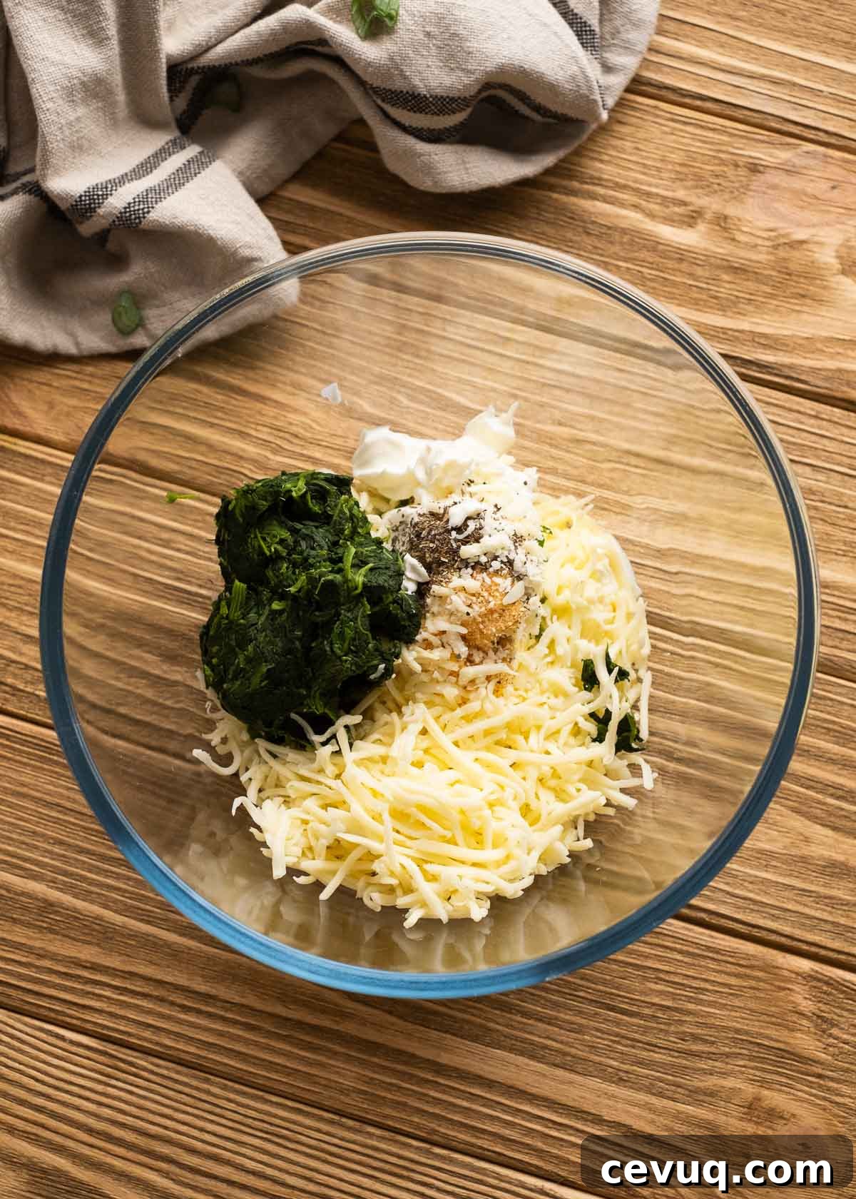 cream cheese, sour cream, shredded cheese, and spinach in a glass bowl