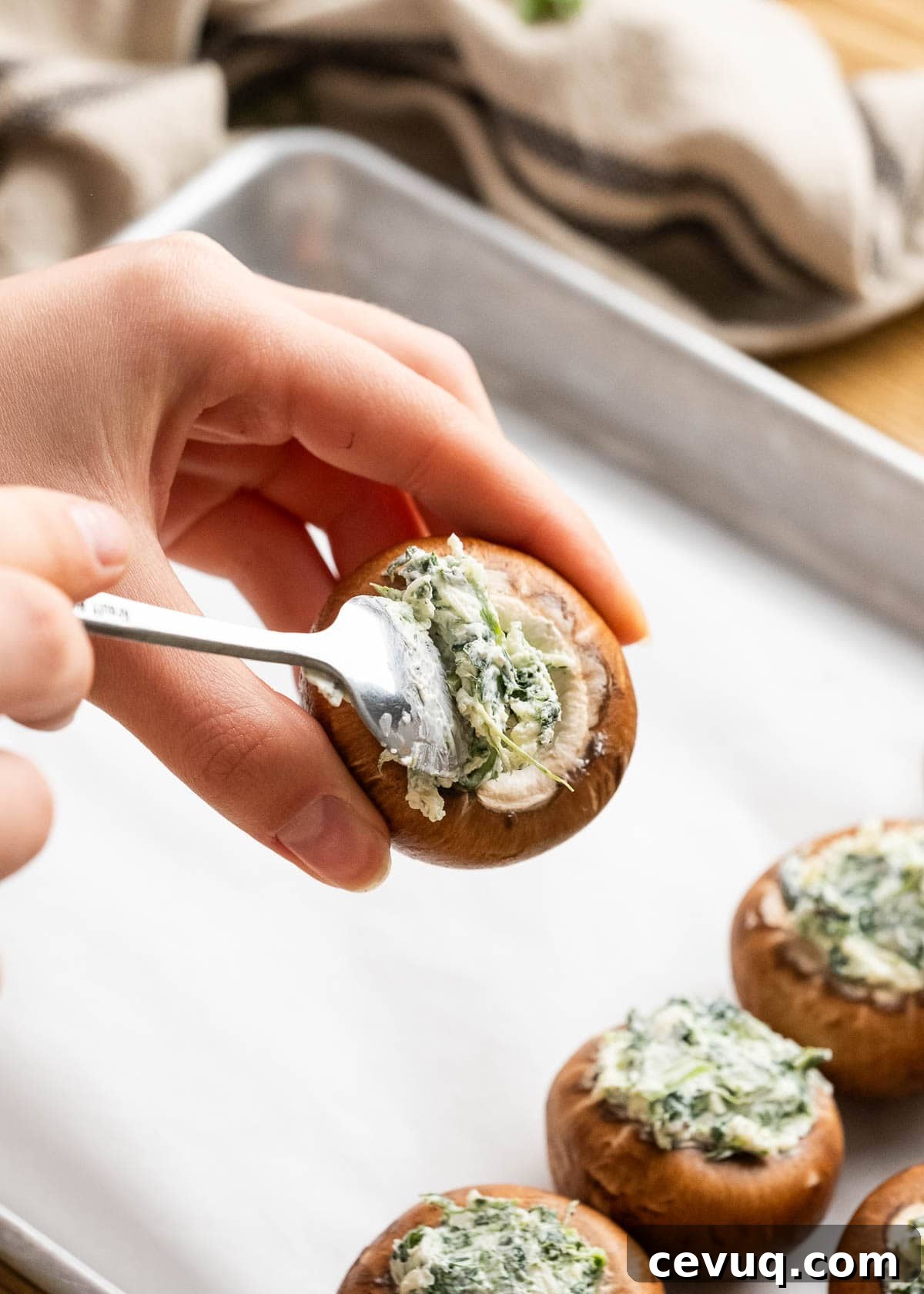 stuffing the mushrooms with the cheesy spinach mixture and placing on a lined baking sheet
