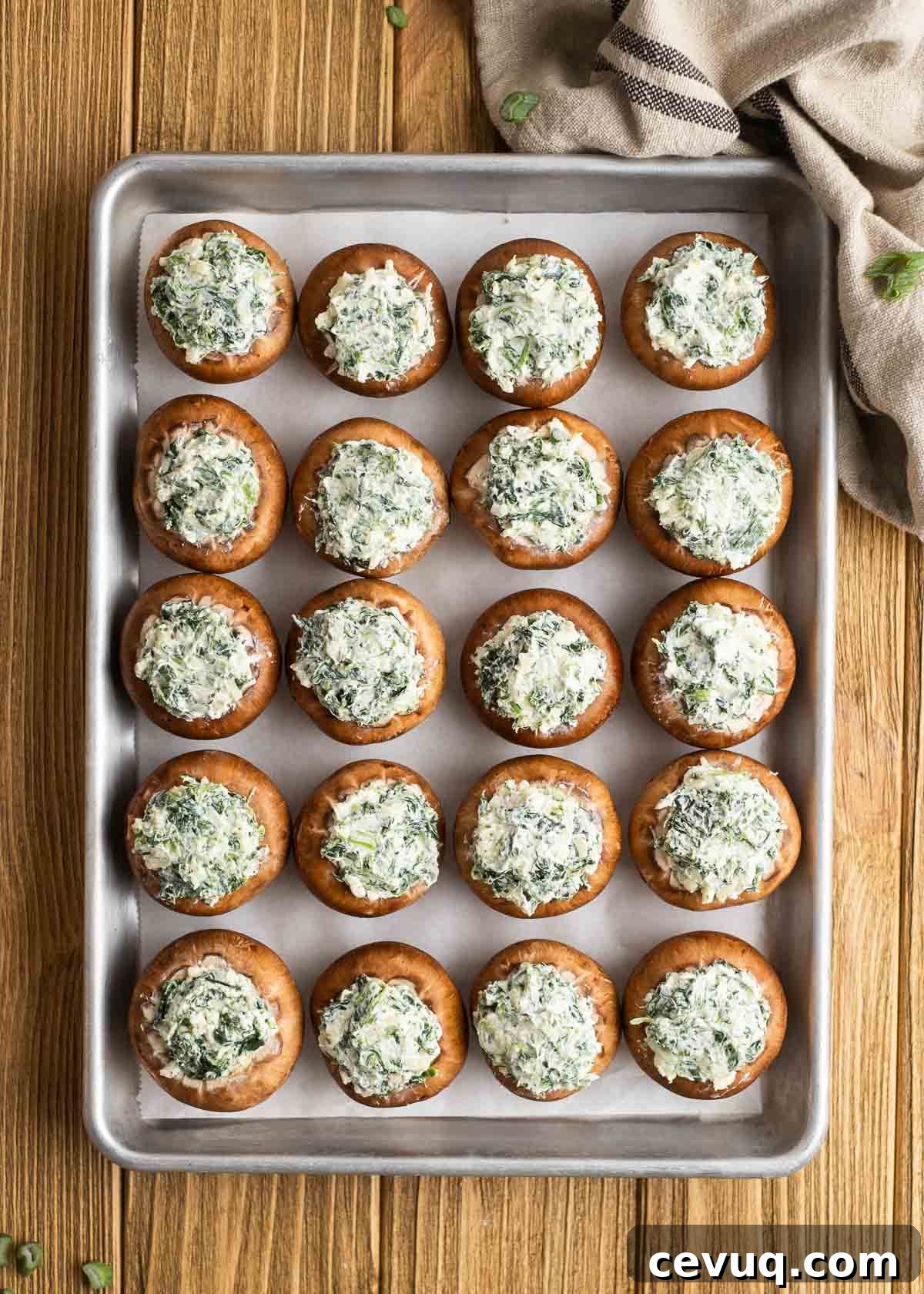 20 baby bella mushrooms stuffed with a spinach and cheese mixture on a lined baking pan