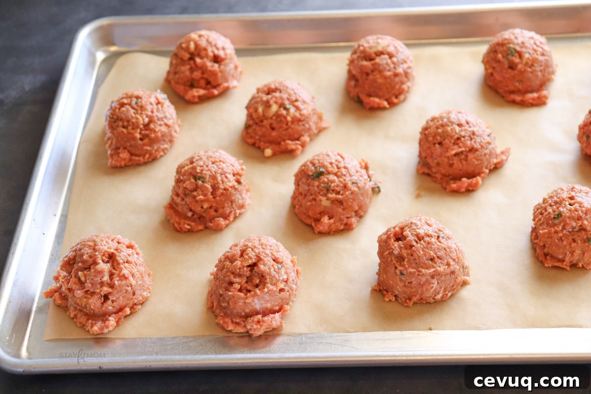 Thai Turkey Meatballs showing meatballs scooped onto a parchment lined baking sheet ready to go in the oven.