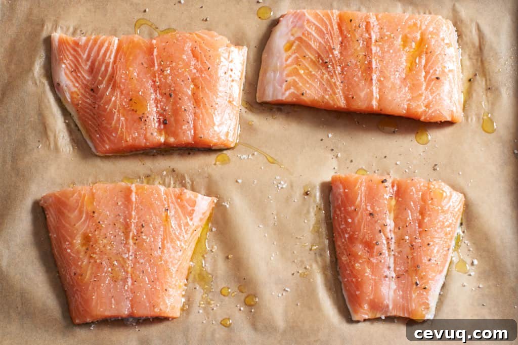 Raw salmon seasoned with salt, pepper and olive oil on parchment paper.
