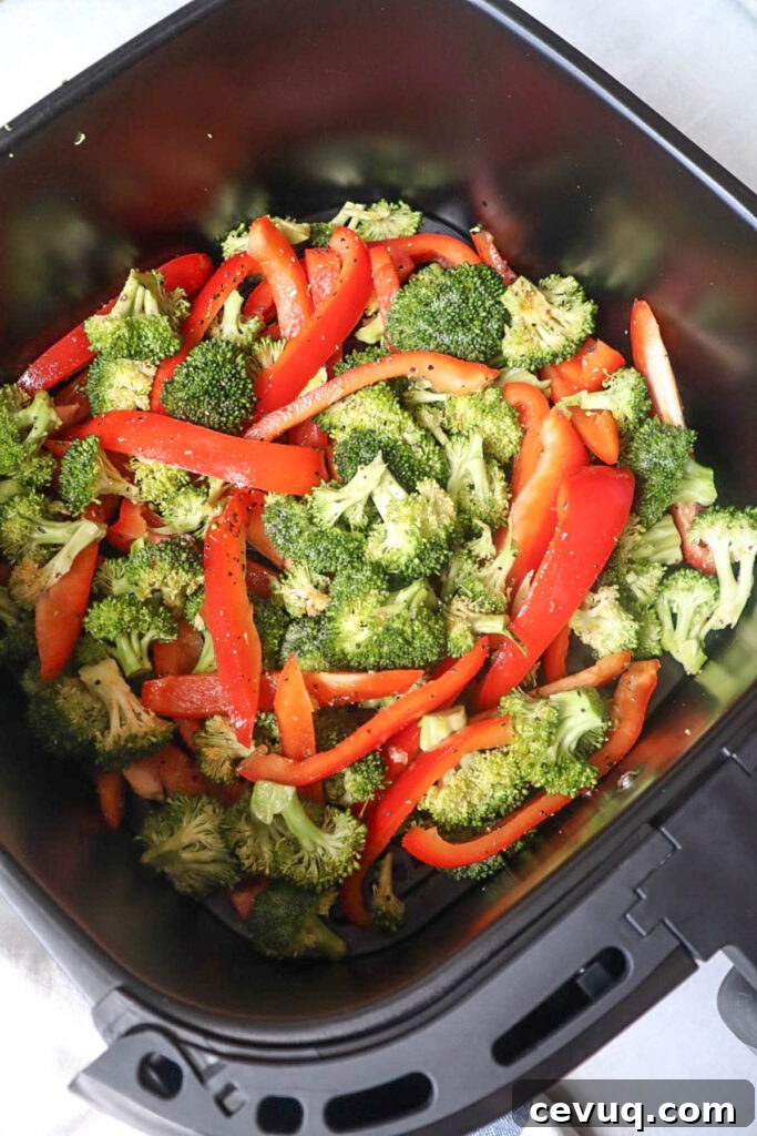 air fryer basket with seasoned red bell pepper and broccoli