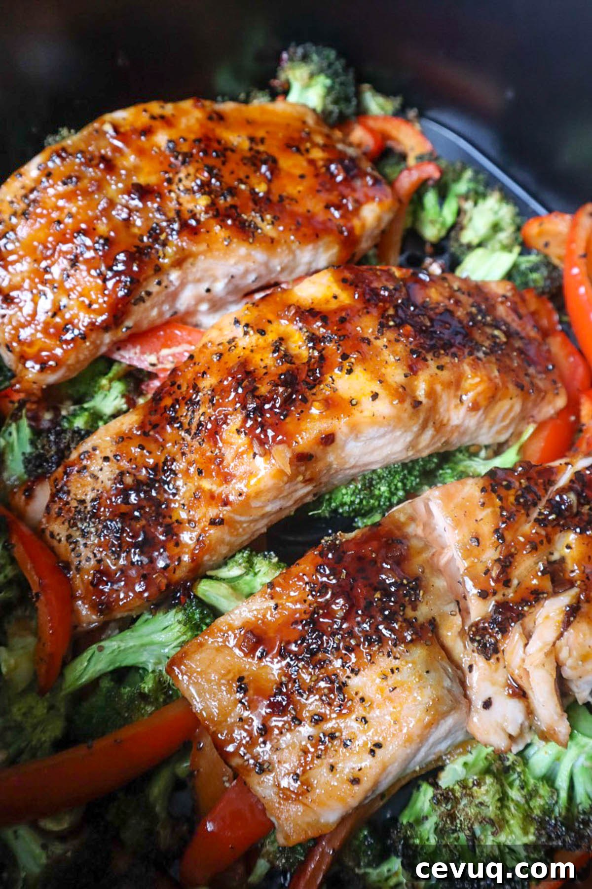 air fryer basket with cooked broccoli, red pepper, and salmon filets