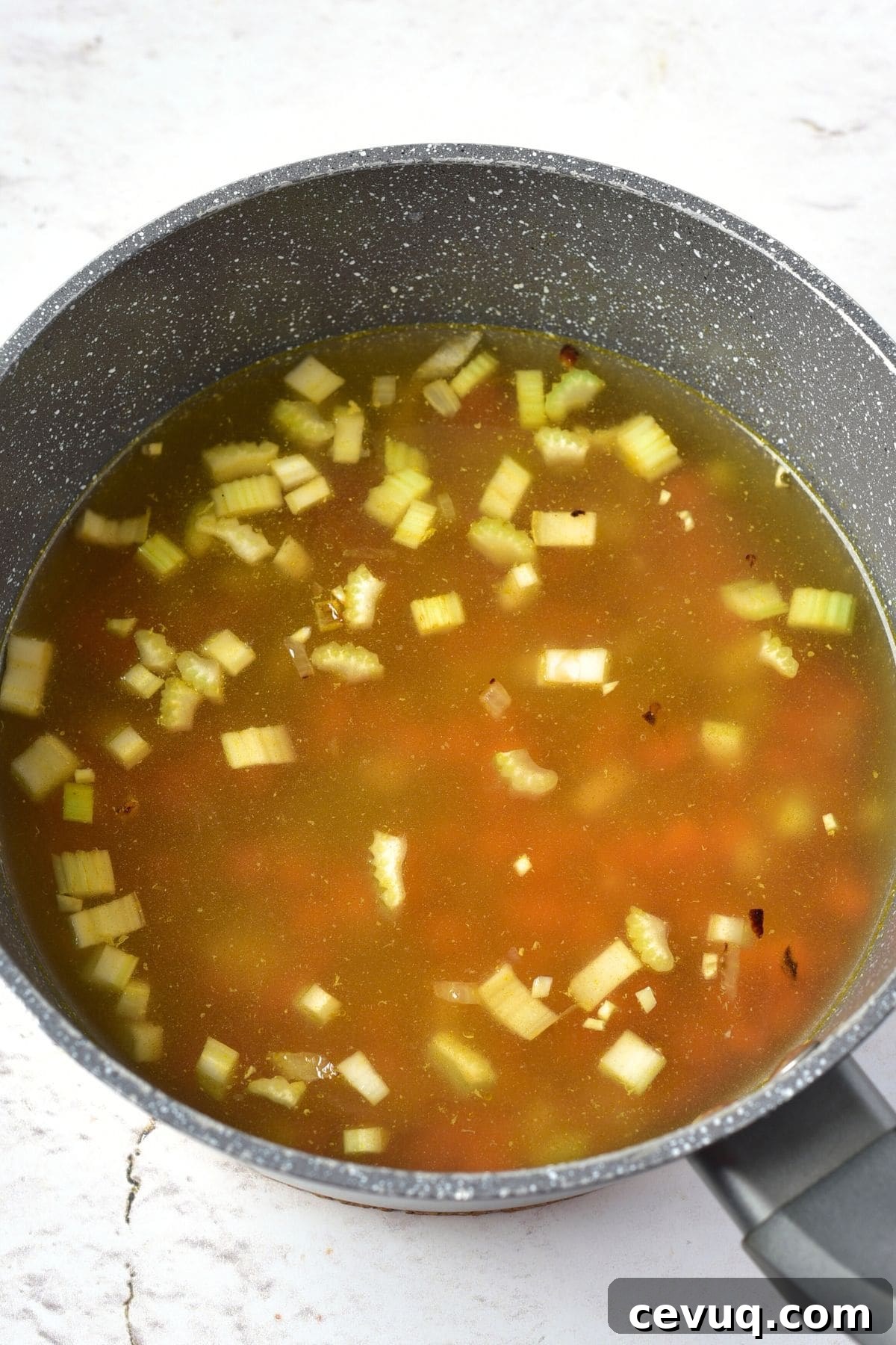 Diced veggies in broth in saucepan