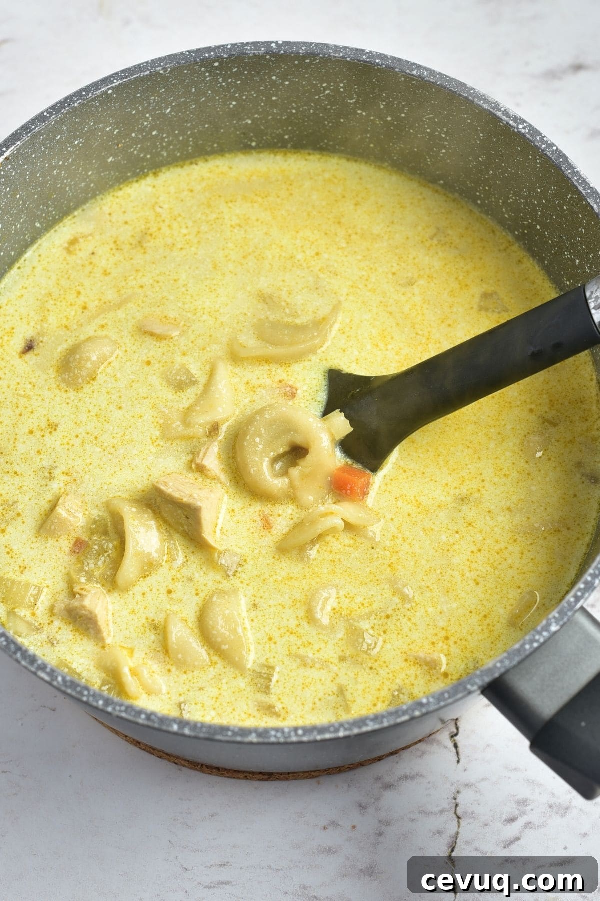 Scooping tortellini from a saucepan with soup