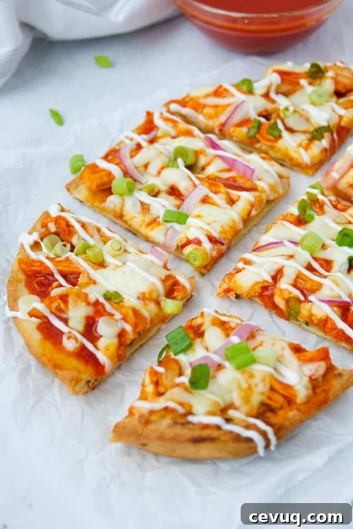 Close-up photo of buffalo chicken flatbread cut into 6 slices on parchment paper