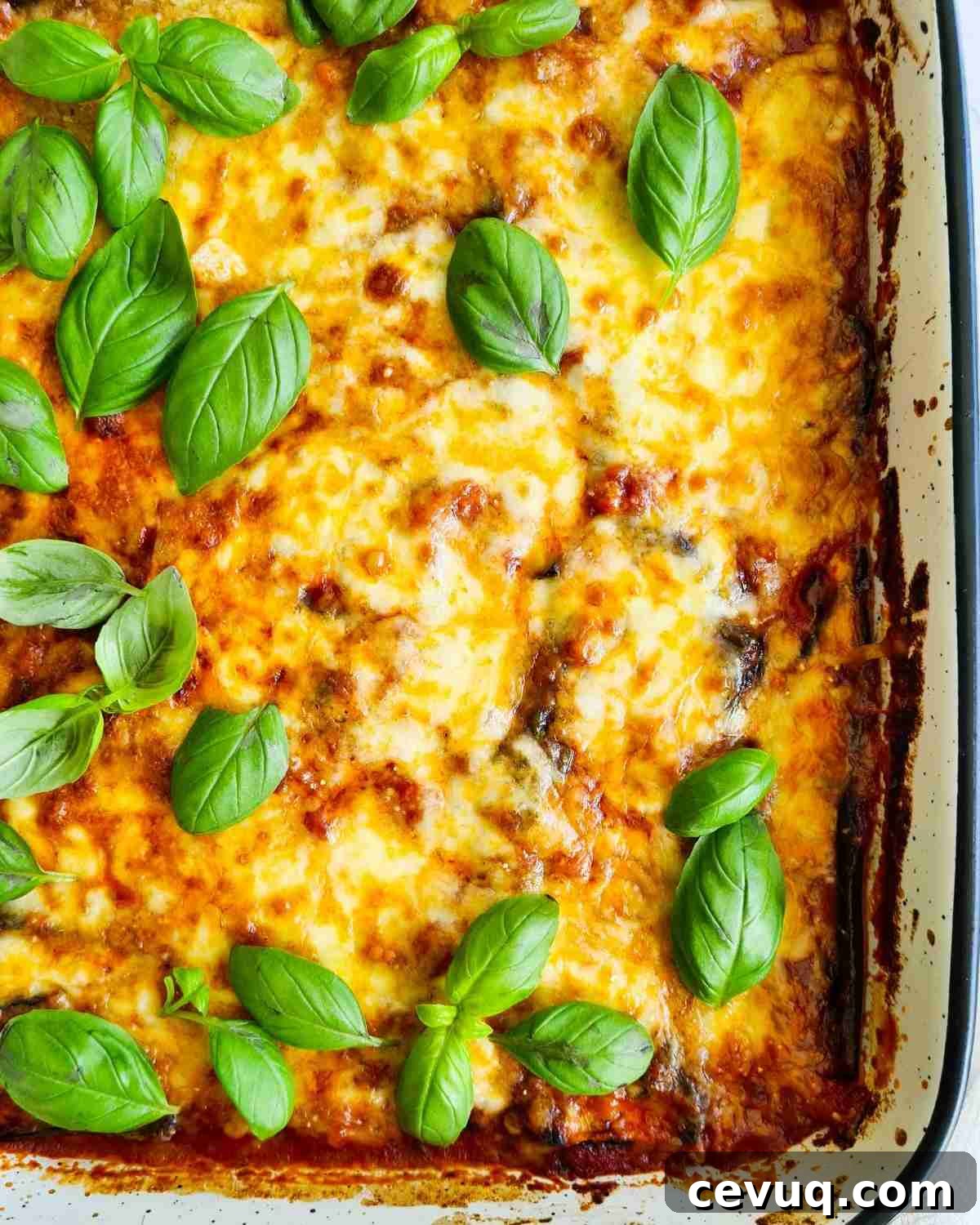 A tray of cheesy bake topped with fresh basil leaves